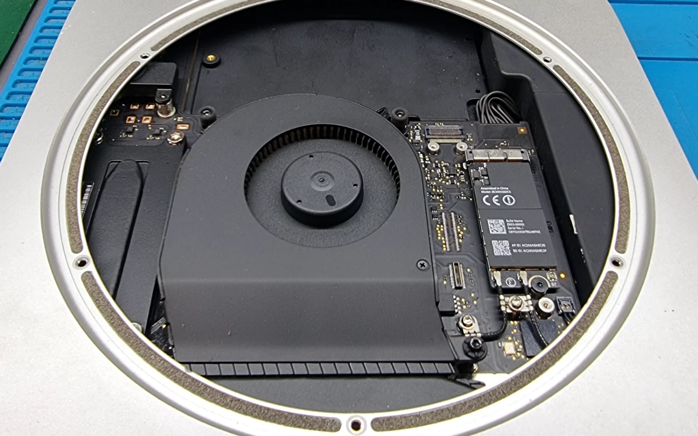 Interior de un Mac mini abierto, con el ventilador, el SSD y la placa a la vista