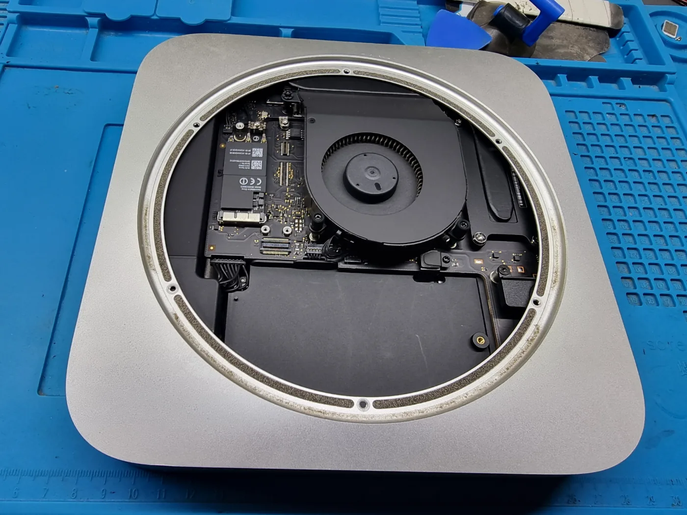 Interior de un Mac mini abierto, con el ventilador, el SSD y la placa a la vista