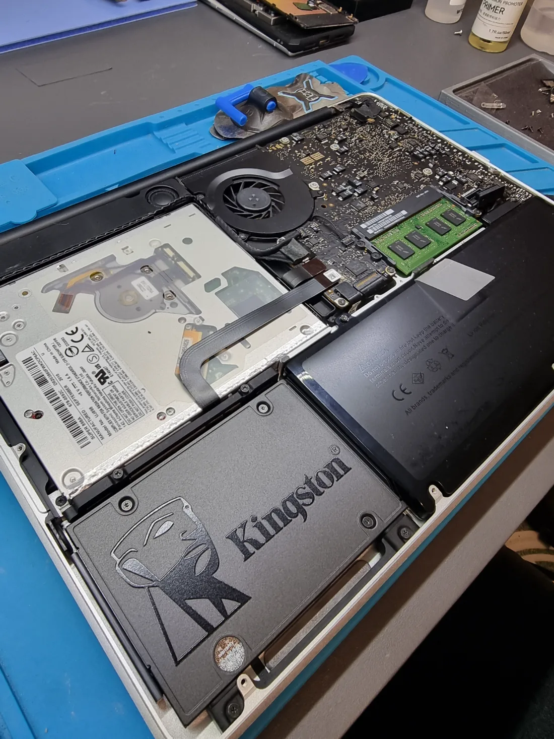 MacBook abierto con un SSD nuevo instalado junto a la batería