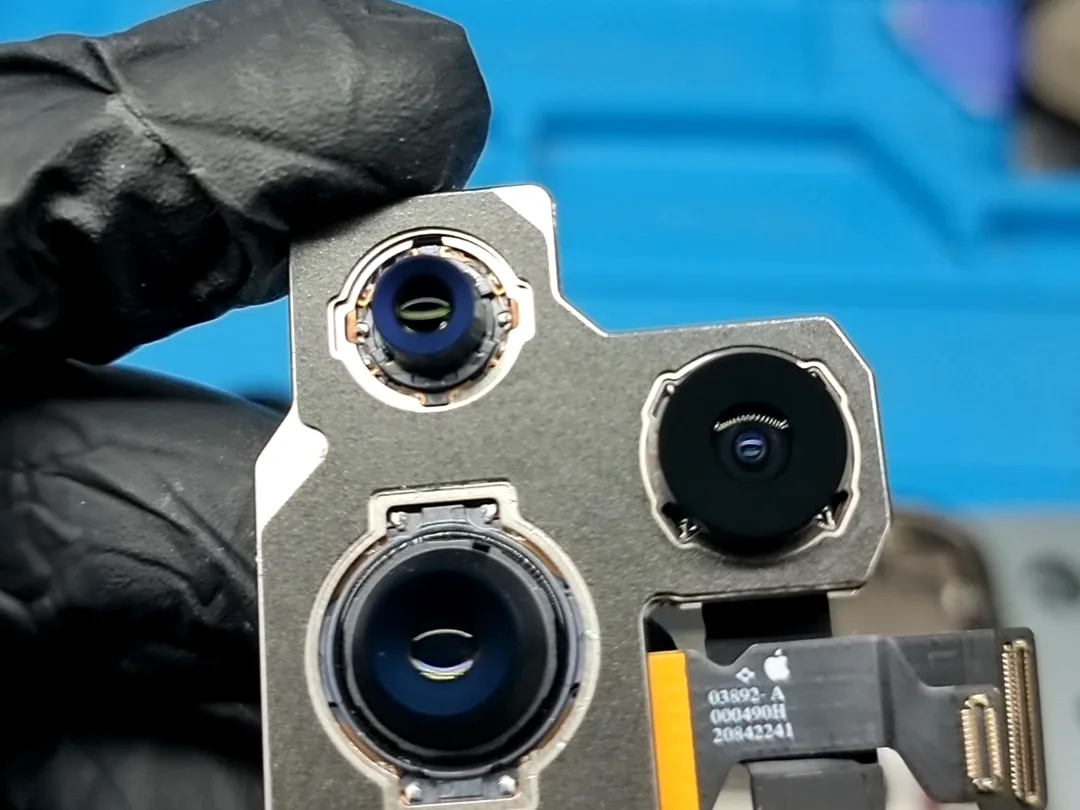 Módulo de cámaras traseras de un iPhone 14 Pro dañado por una caída, en la mano del técnico