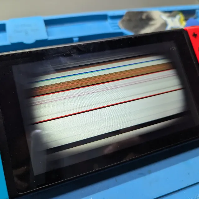Nintendo Switch con líneas en la pantalla sobre la mesa de trabajo