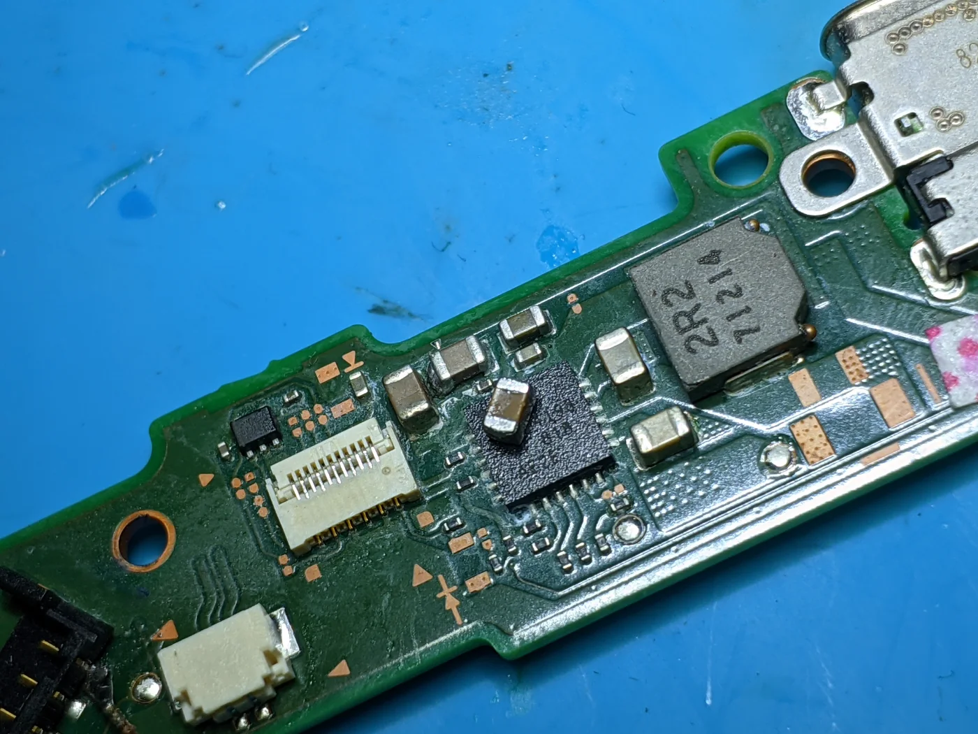 Placa de carga de una Nintendo Switch vista de cerca, con el conector USB-C y el condensador en cortocircuito